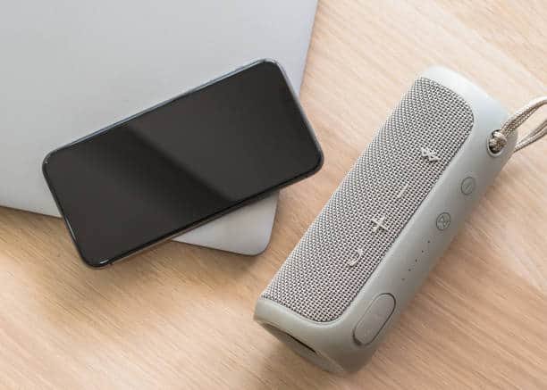 Enceinte Bluetooth posée sur une table avec un smartphone à sa gauche